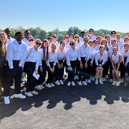A large group of students pose for a photo while working the 2022 Presidents Cup in Charlotte, N.C.