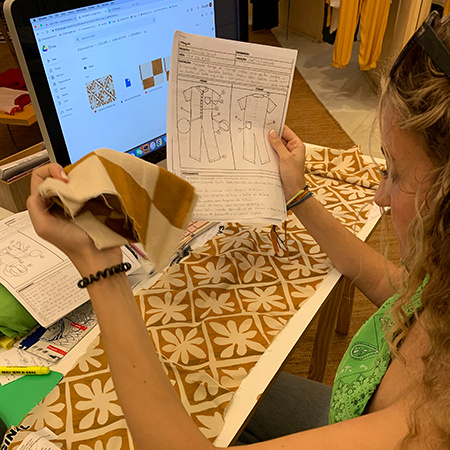 A student doing an internship with a jewelry design company in Brazil looks at design plans for clothing.