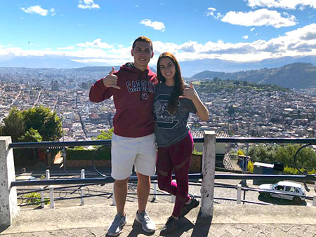 Two HRTM students pose "spurs up!" at an overlook in Quito, Ecuador. The students were able to visit the city while spending a semester studying in the Galapagos.