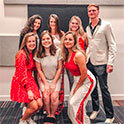 Fashion Board at UofSC students wearing garnet, white, black and tan outfits, pose in front of a gray, tan, and garnet background.