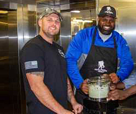 Two veterans stand near a blender after making guacamole