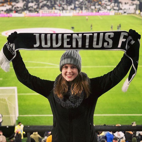 Magellan Scholar Morgan Brueter holds up a Juventis sign while conducting research during a soccer game. Bueter’s interest in sponsorship conflict, a common occurrence in professional sports, took her to Torino, Italy, where she focused her research on the clash between professional soccer player Cristiano Ronaldo, a Nike sponsored athlete, and his club, Juventus, which is sponsored by Adidas.