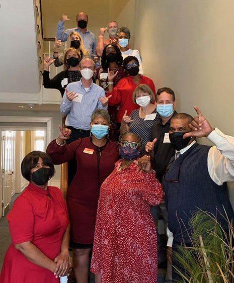 Masked HRSM faculty and staff gather for a photo on the staircase inside McCutchen House during a luncheon for participants in the Diversity, Equity and Inclusion Certificate Program