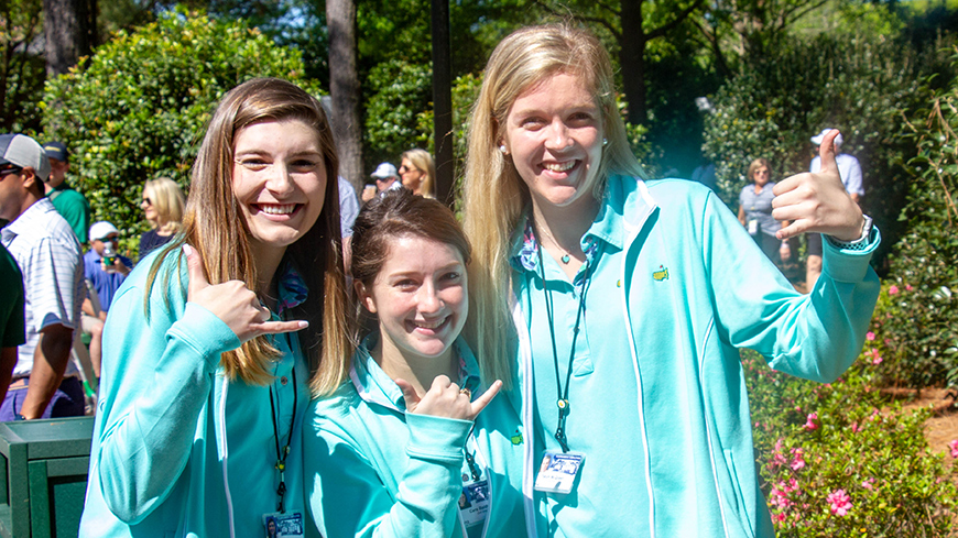 Three students working the Masters give a Spurs Up