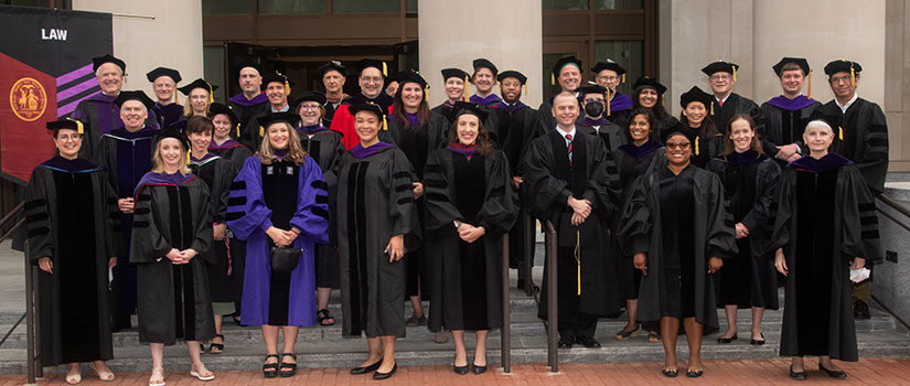 Group shot of faculty taken in their academic regalia on the front steps of the School of Law.