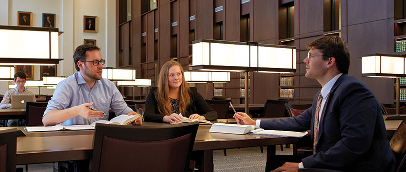 Students interacting with professor in law library