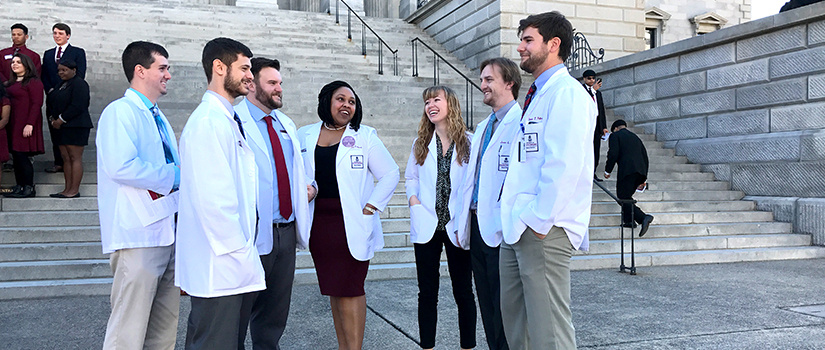 Students in white coats on the State House steps