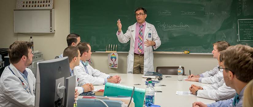 Professor teaching students in lab coats