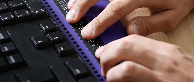 Close-up image of hands typing on a braille keyboard