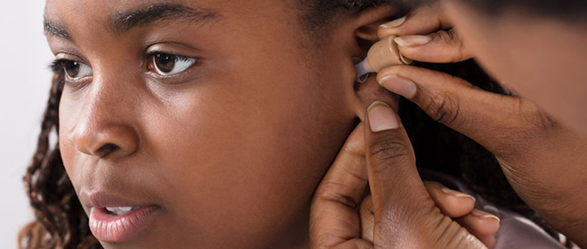 A health provider checks a girl's hearing aid