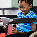 smiling child in wheelchair looking at a tablet
