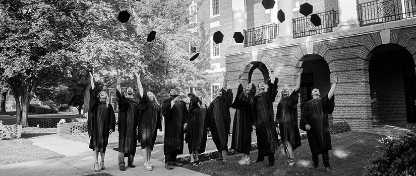 Students in graduation robes tossing caps