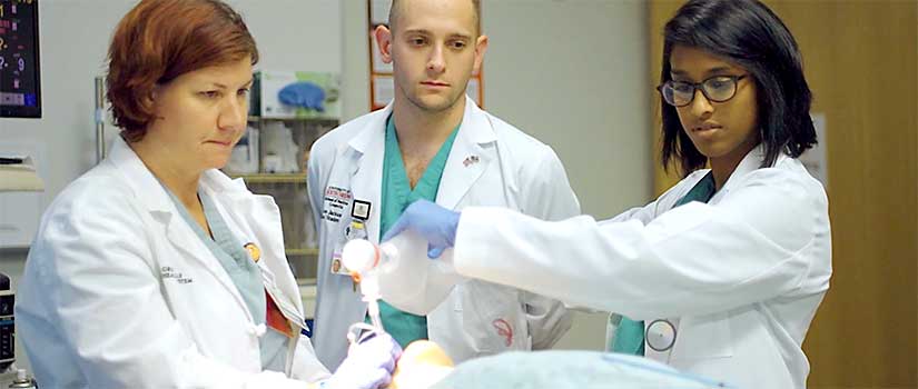 Professor watches medical students intubate a patient in the simulation lab.