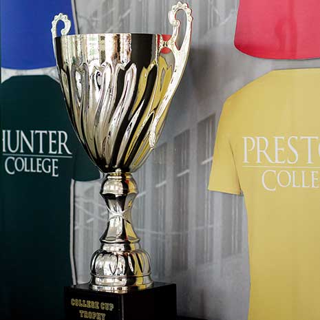 The College Cup trophy displayed with the five college t-shirts.