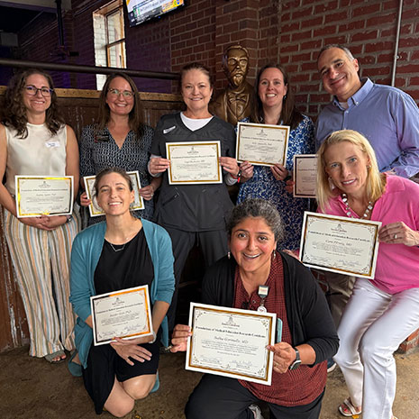 A group of staff smiling with certificates.