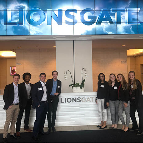 marketing scholar students standing in front of the Lion's Gate logo