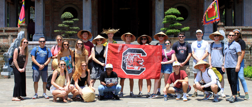 Group of UofSC students in Vietnam, holding the UofSC flag