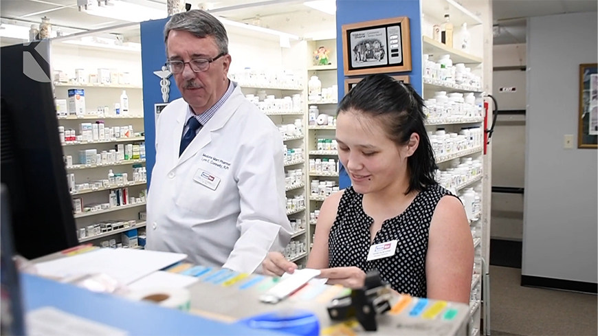 Pharmacist and staff member behind a counter
