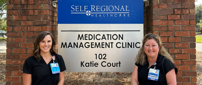 Alumni in front of Self Regional Hospital sign