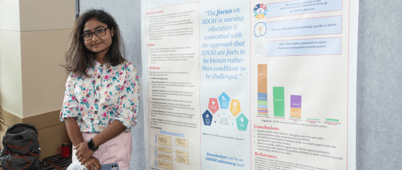 Student standing in front of a research poster