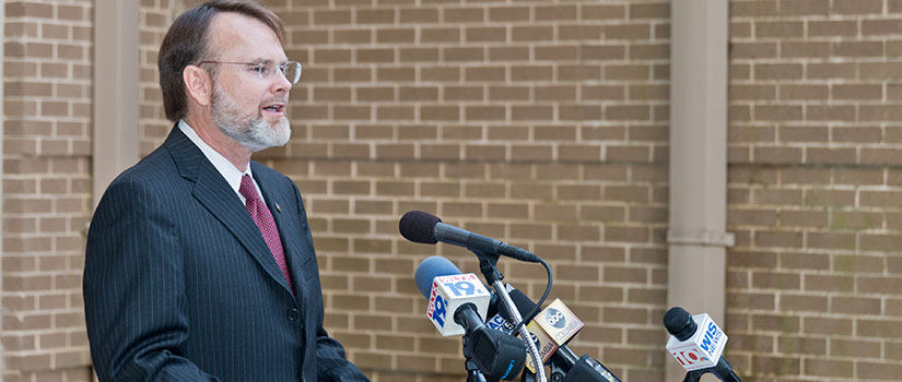 G. Thomas Chandler, Dean of the Arnold School of Public Health, standing at a podium giving a press briefing