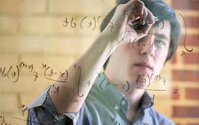 Man writing math equations on a piece of glass