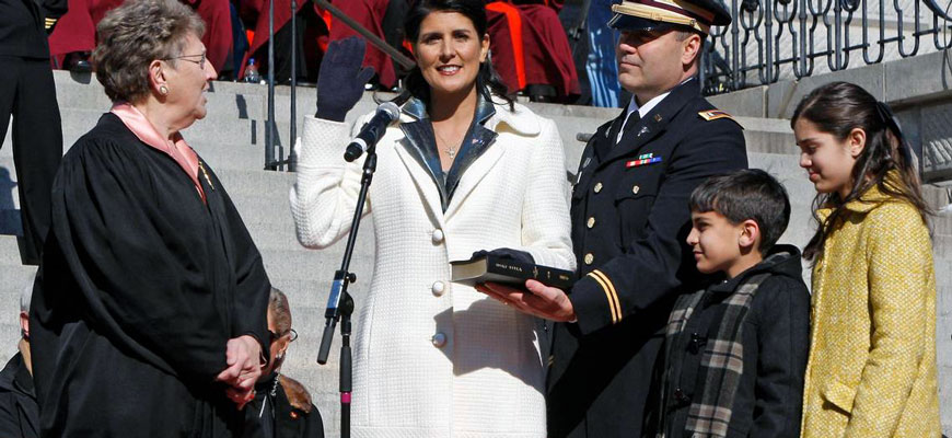 joan toal administers oath of office to Nikki Haley in 2011 while Haley's husband and their son and daughter look on