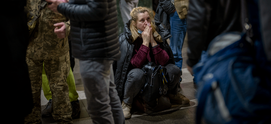 A woman in Ukraine appears to pray as she waits for a train out of Kyiv