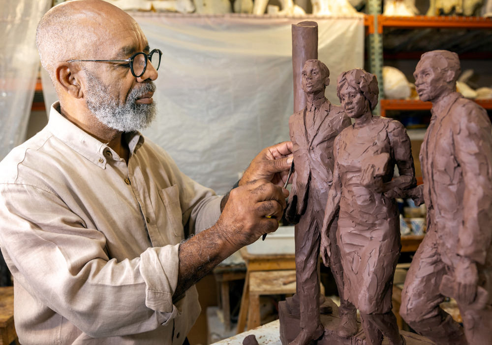 Sculptor Basil Watson works on a small scale version of a planned sculpture of three people