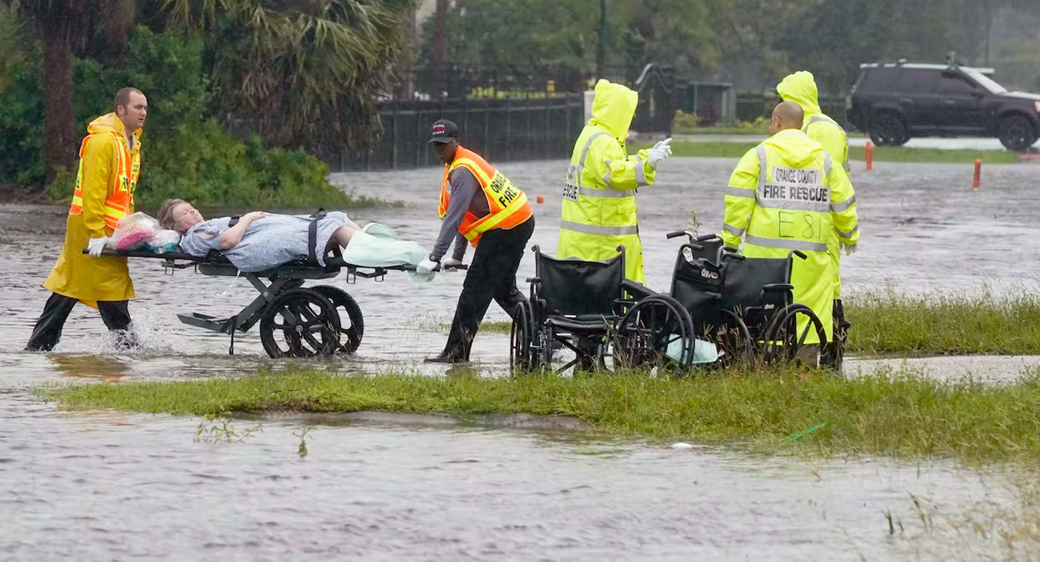 2 health care workers move a woman on a stretcher through floodwaters in Florida
