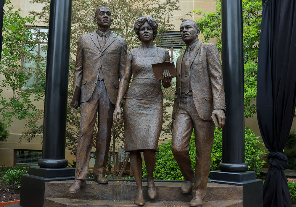 bronze monument depicting three people standing in a doorway