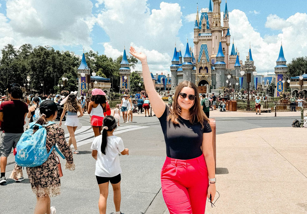 Woman with arm up in front of Walt Disney World castle