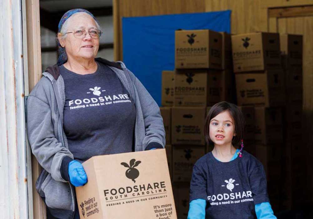 FoodShareSC volunteer carries a box of fresh produce.