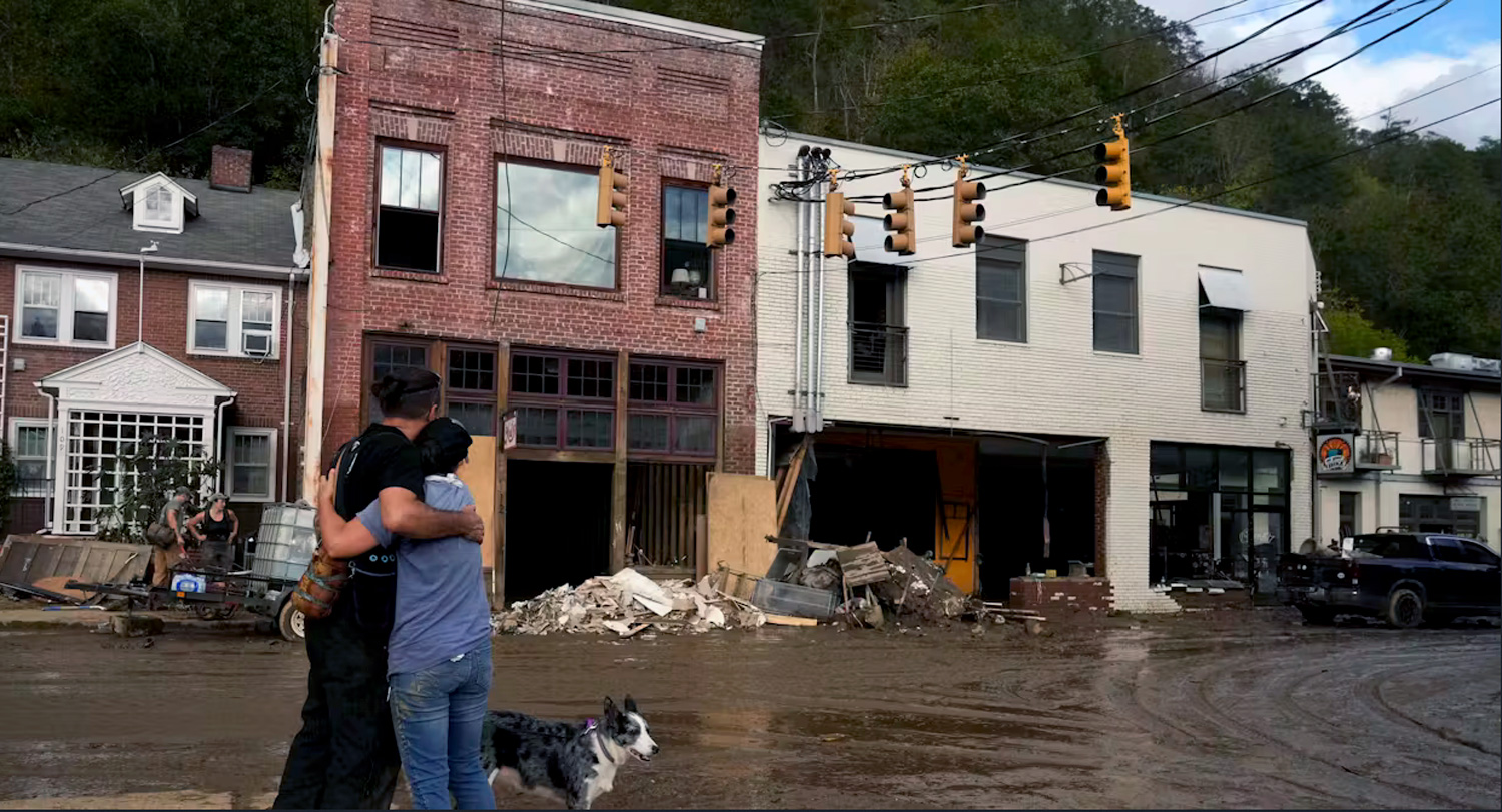 a man and woman embrace while looking at flooded buildings