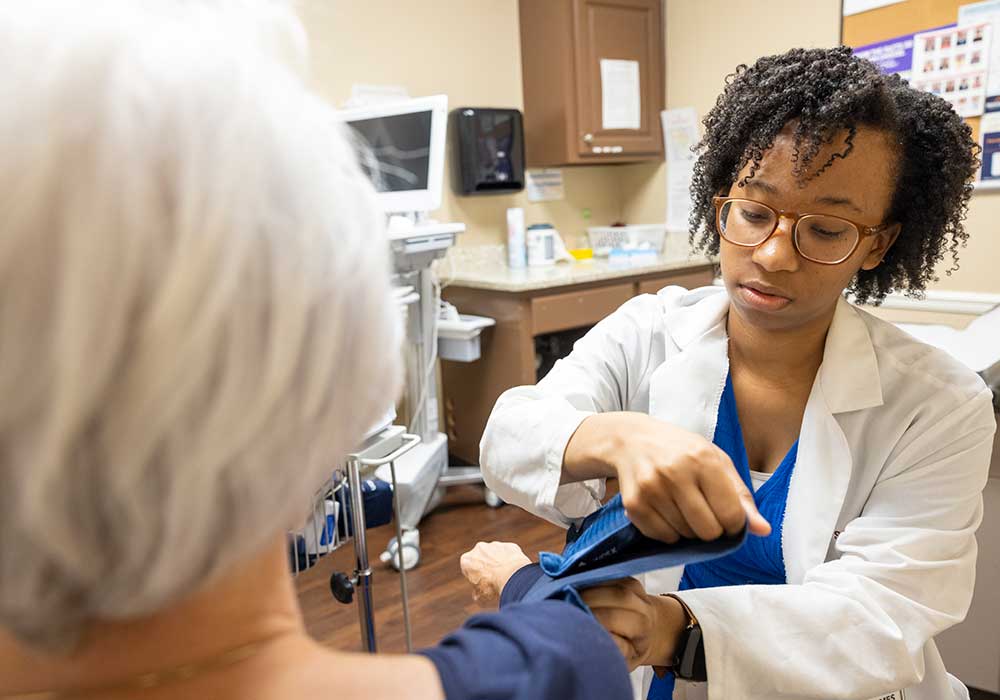 Rural pharmacist assist patient with blood pressure reading.