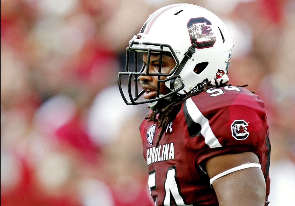 man in garnet football jersey and white helmet standing straight up