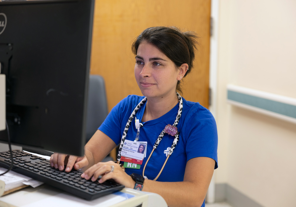 woman in scrubs at a computer