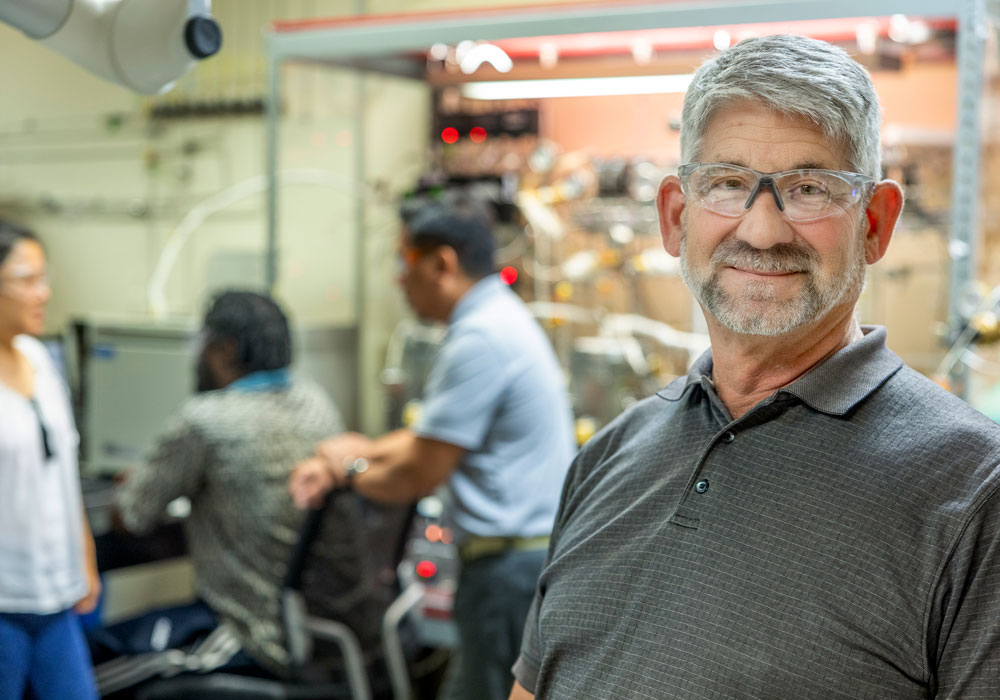 a man wearing safety glasses stands in a lab