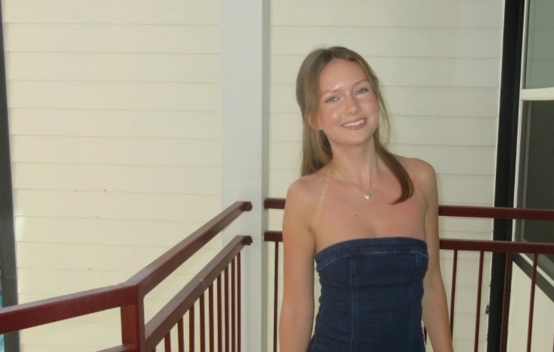 a woman stands on a porch with a house in the background