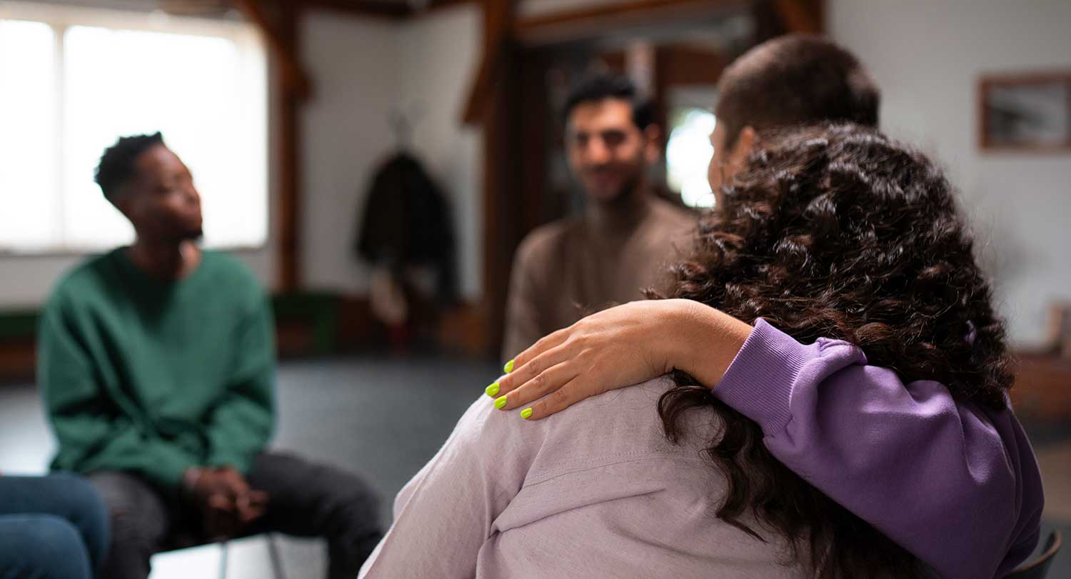 Woman comforts peer during group counseling session