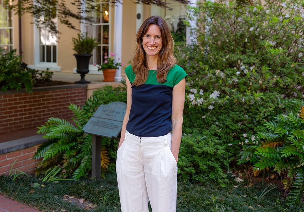 a woman standing in front of greenery