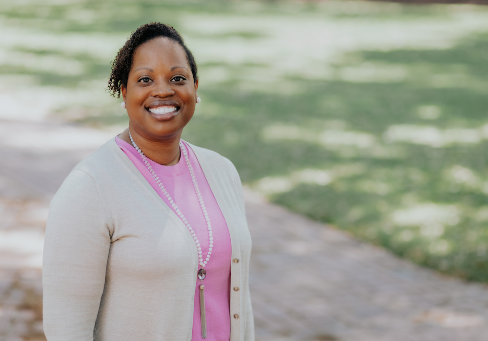 woman in pink shirt and beige cardigan smiles at camera