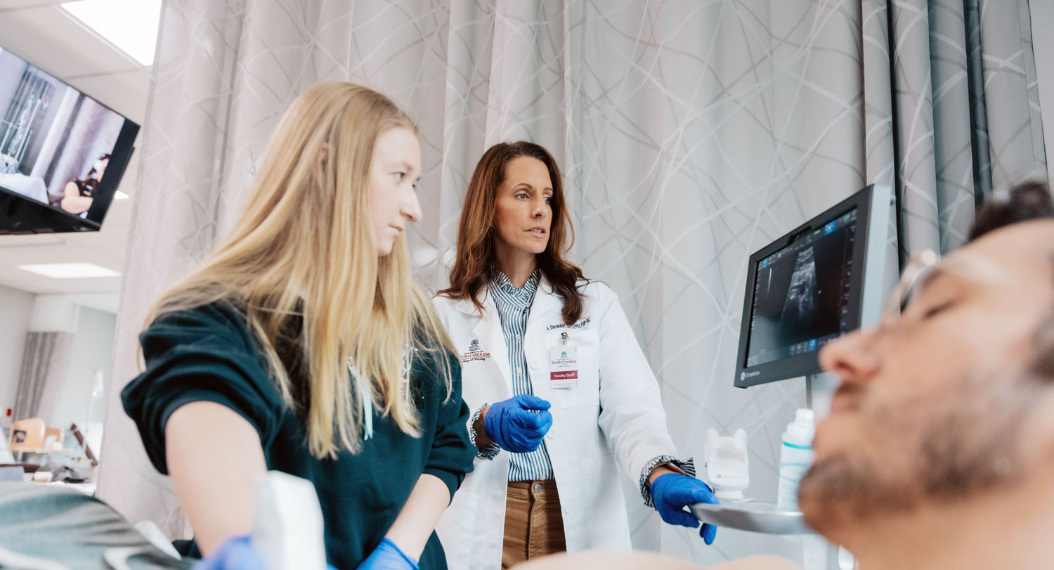 Two people look at an ultrasound with the patient in the foreground