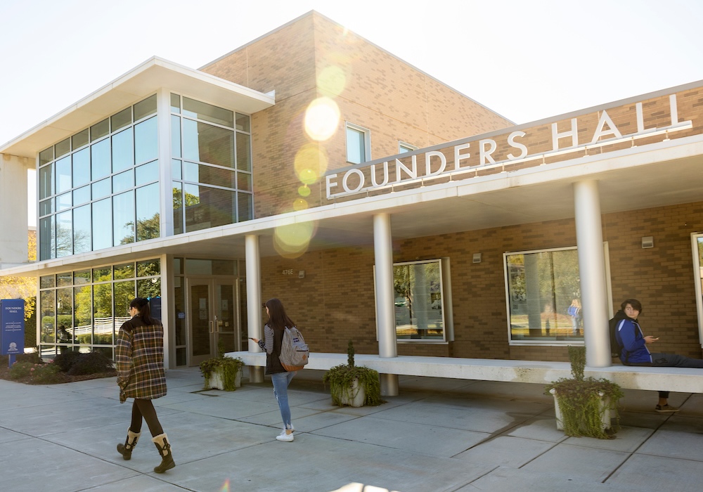 sign with white letters on a brick building reading founders hall