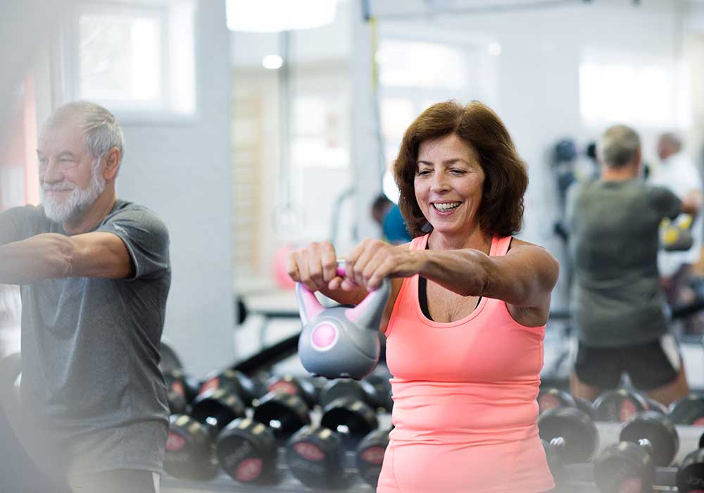 Woman works with kettle bell in a gym.