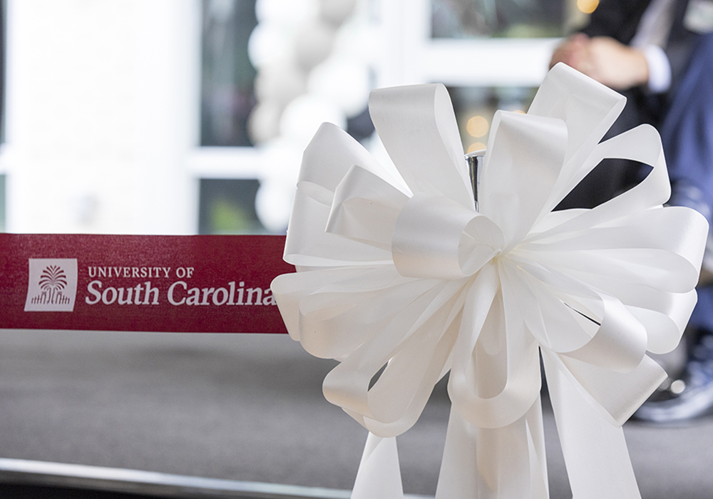 University of South Carolina garnet ribbon stretches across opening and ends in white bow during a ribbon cutting ceremony