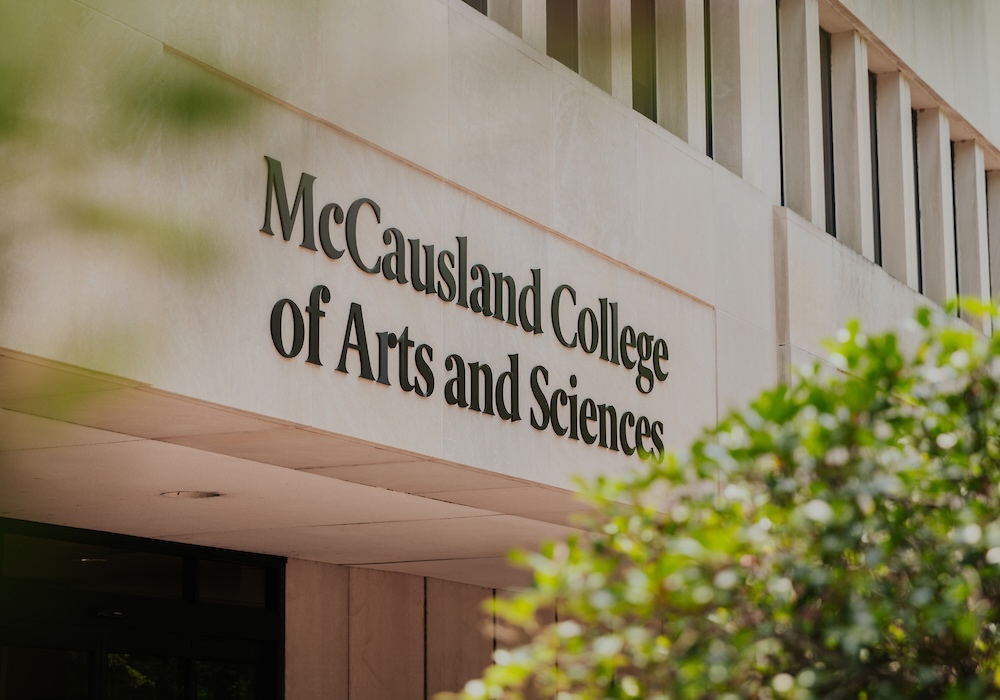 beige building with black "McCausland College of Arts and Sciences" on the facade