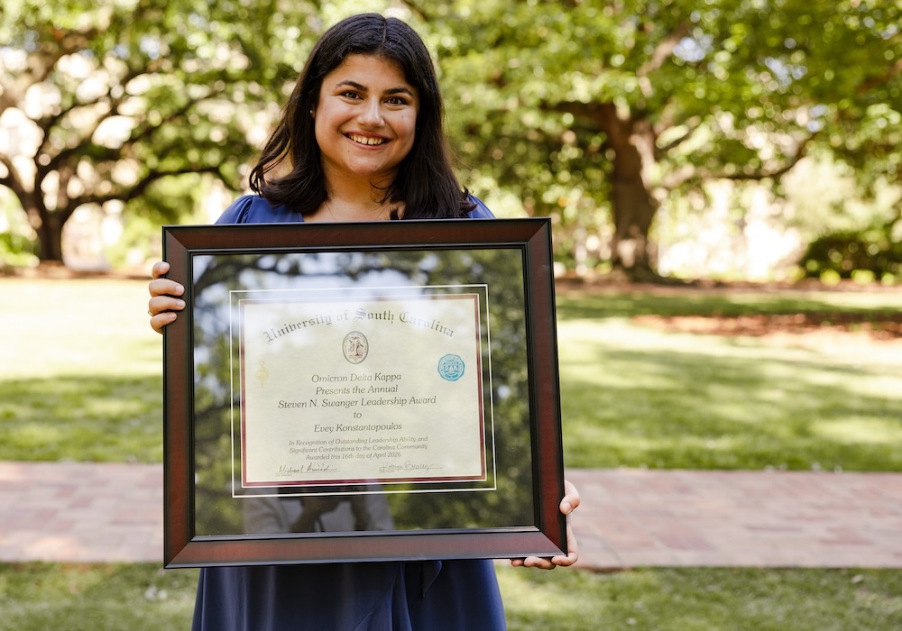 woman in blue dress holding framed award