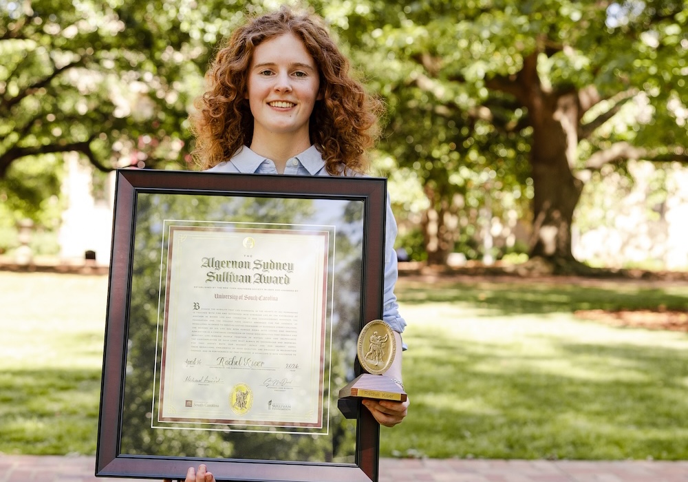 woman in blue shirt holding framed award