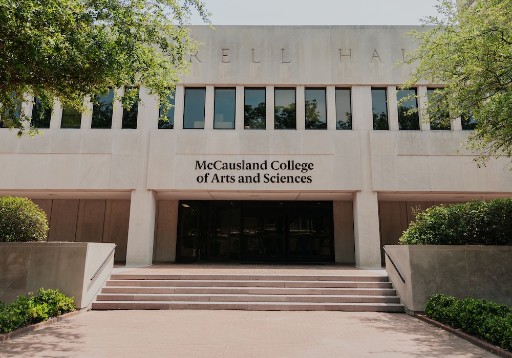 beige building with black "mccausland college of arts and sciences" on the facade